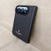 A black textured leather phone case with a raised camera bezel, featuring the 'MediaDevil London' logo, shown on a beige linen background.